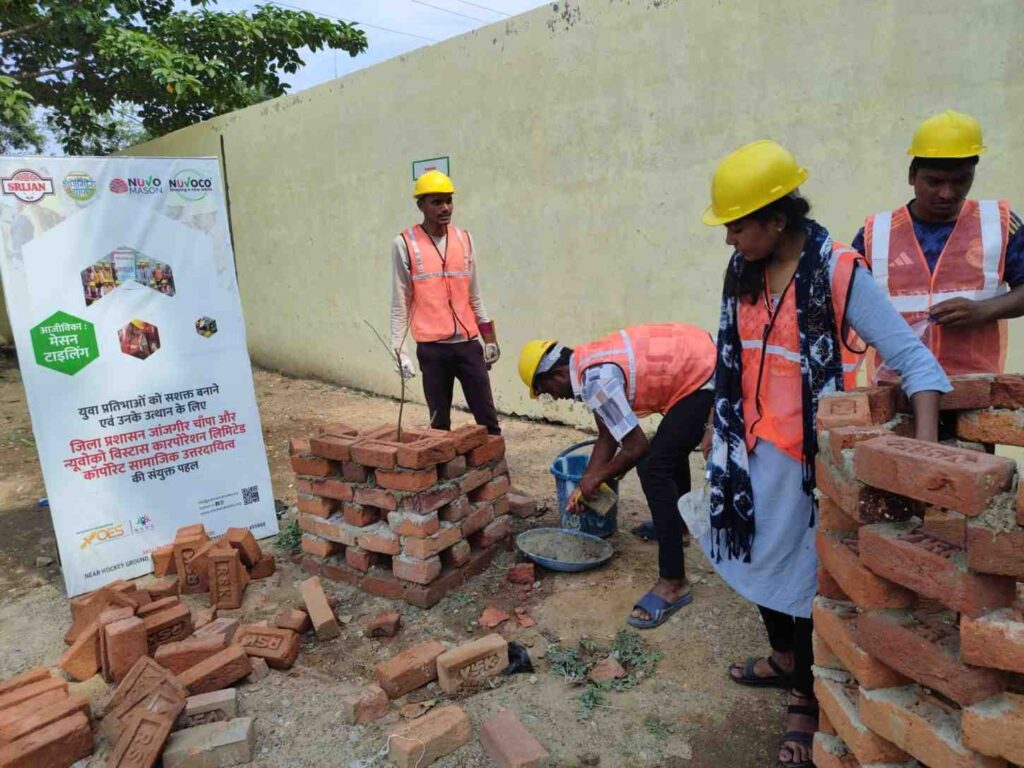 Youth trainees in safety helmets and high-visibility vests practising masonry and tiling skills at an OES construction trades vocational training programme in India